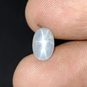 Puede incluir: Una piedra preciosa de zafiro estrella ovalada blanca con un patr&oacute;n en forma de estrella en el centro.