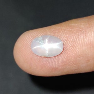 Puede incluir: Una piedra preciosa ovalada blanca con un patr&oacute;n en forma de estrella en el centro.