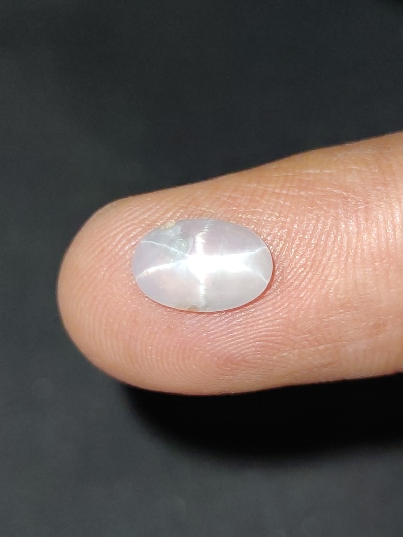 Puede incluir: Una piedra preciosa ovalada blanca con un patr&oacute;n en forma de estrella en el centro.