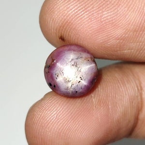 Peut inclure: Une pierre précieuse de rubis étoilé ronde et rose avec un reflet en forme d'étoile au centre.