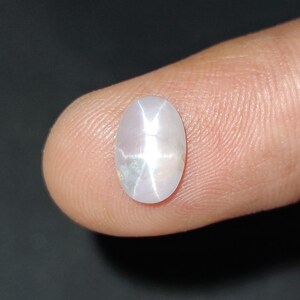 Puede incluir: Una piedra preciosa ovalada blanca con un patr&oacute;n en forma de estrella en el centro.