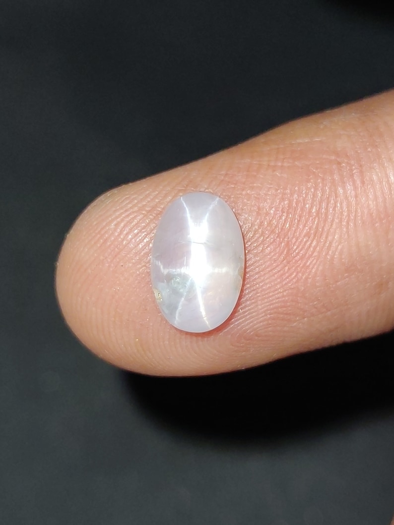 Puede incluir: Una piedra preciosa ovalada blanca con un patr&oacute;n en forma de estrella en el centro.