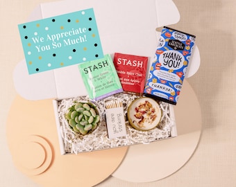May include: A white gift box filled with a succulent plant, two tea bags, a candle, matches, and a chocolate bar. The box is decorated with a card that says "We Appreciate You So Much!" and the chocolate bar says "Thank You!"