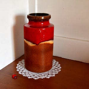 Może przedstawiać: Czerwono-brązowy ceramiczny wazon z szkliwioną powierzchnią. Wazon ma zaokrąglony kształt i szeroki otwór.
