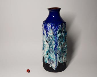 May include: A blue and white ceramic vase with a textured, dripping glaze. The vase has a wide mouth and a narrow base.