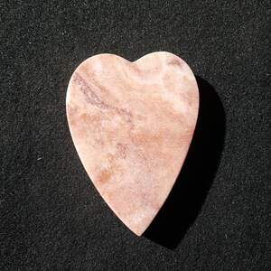 Può includere: Un pezzo di marmo rosa e bianco a forma di cuore con un motivo marmoreo.