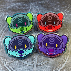 Peut inclure: Quatre épingles en émail colorées représentant un animal de dessin animé portant un casque avec un motif circulaire. Les épingles sont vertes, rouges, bleues et violettes.