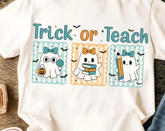 May include: A white t-shirt featuring the text Trick or Teach in teal and orange. Below the text are three rectangular frames containing white ghost characters. The ghosts are decorated with bows, holding a pumpkin bucket, books, and a pencil.