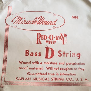 May include: A package of Red-O-Ray Bass D String, with the text "Miracle Wound" in a red oval. The text "Bass D String" is in large red letters. The package is from Kaplan Musical String Co., U.S.A.