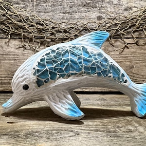 May include: A blue and white mosaic dolphin figurine. The dolphin is in a leaping pose with its tail raised. The mosaic tiles are arranged in a pattern that resembles scales.