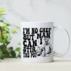 May include: White ceramic mug with a black graphic of a skeleton chef and the text "I'm no chef but man can I stir the pot".