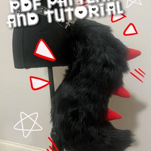 May include: A black faux fur tail with red spikes, attached to a black belt. The text "PDF PATTERN AND TUTORIAL" is displayed in white. The tail is displayed on a black mannequin.