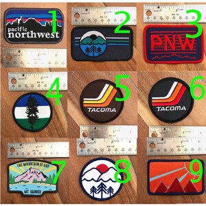 May include: Nine embroidered patches with various designs, including a mountain range, a pine tree, and the words "Pacific Northwest" and "Tacoma".