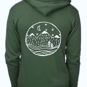 May include: A dark green hoodie with a white circular graphic on the back. The graphic depicts a mountain range, trees, a crescent moon, and stars. The hoodie has a hood and a zipper down the front.