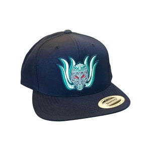 May include: A black and green baseball cap with a graphic of a creature's face with red eyes. The cap has a black brim and a white "Snapback" label on the back.