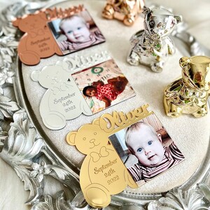 May include: Four gold-toned, silver-toned, and rose gold-toned teddy bear photo frames with a baby's photo and the name "Oliver" and birthdate "September 24th, 2022".