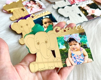 May include: Gold mirror acrylic elephant ornament with a photo of a baby girl wearing a floral headband. The ornament has the name "Grace" written on it.