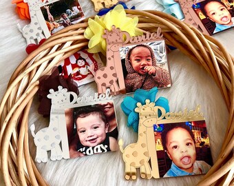 May include: A wicker wreath decorated with multiple gold, silver, and rose gold giraffe photo frames. Each frame features a different baby photo and the name "Daniel".