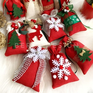 Puede incluir: Surtido de peque&ntilde;as bolsas de regalo de tela roja y blanca con diversas decoraciones de tem&aacute;tica navide&ntilde;a, incluyendo copos de nieve, renos y &aacute;rboles de Navidad. Las bolsas est&aacute;n llenas de una sustancia blanca y atadas con una cinta.