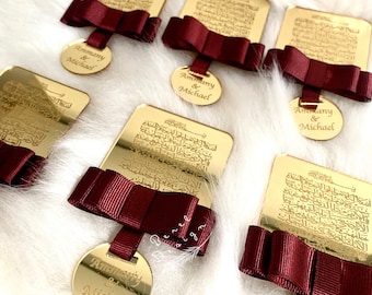 May include: Five gold-coloured rectangular plaques with Arabic script, each with a burgundy bow and a round gold-coloured tag with the text "Ammany & Michael" engraved on it.