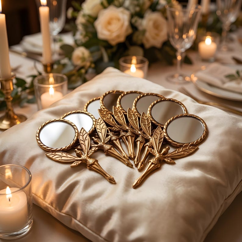 May include: A collection of small, round hand mirrors with gold-toned metal handles shaped like fairy figures with detailed wings. The mirrors are arranged in a cluster, each featuring a circular reflective glass surface and a decorative, textured handle.