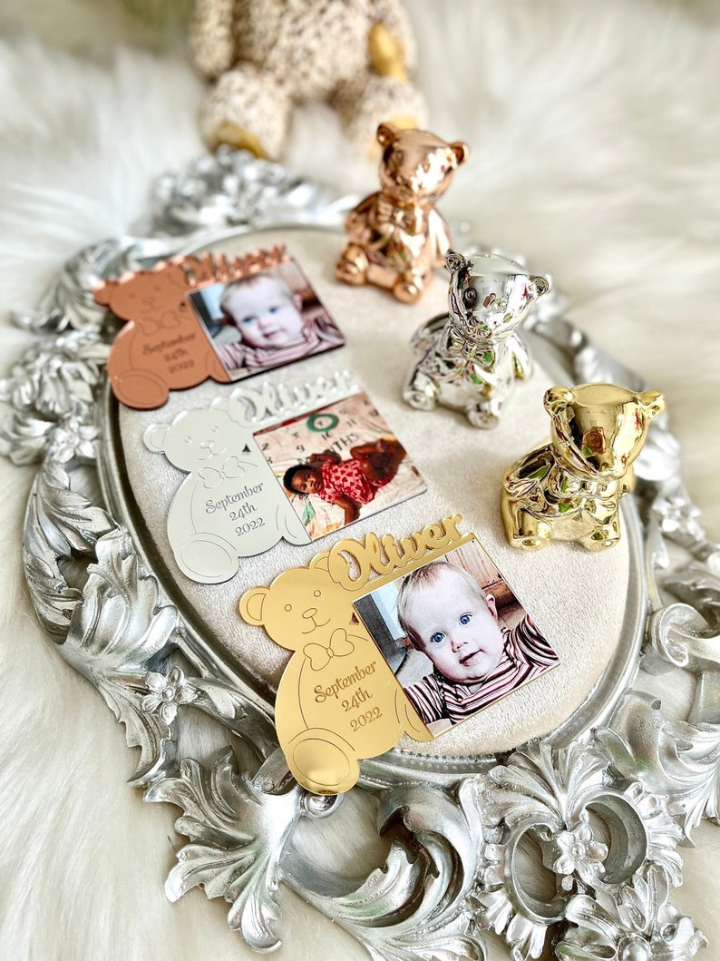 May include: Four gold-toned, silver-toned, and rose gold-toned teddy bear photo frames with a baby's photo and the name "Oliver" and birthdate "September 24th, 2022".