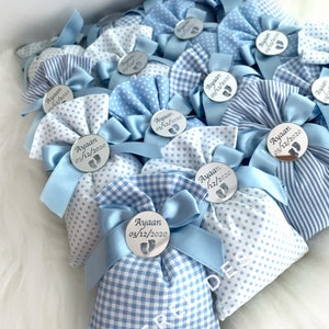 May include: Blue and white gingham favour bags with a silver circle tag that says "Ayaan 03/12/2020" and a small footprint design.