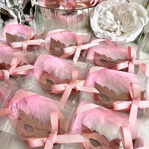 May include: Pink and gold party favours with a mask design and the name "Sienna's" and the date "May 6, 2023".