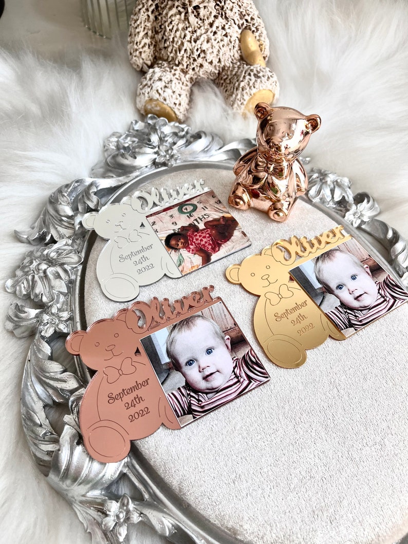 May include: Three personalized photo frames shaped like teddy bears with the name "Oliver" and the date "September 24th, 2022". The frames are silver, gold, and rose gold.