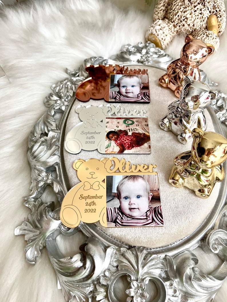 May include: Gold, silver, and rose gold teddy bear photo frames with a baby's photo and the name "Oliver" and the date "September 24th, 2022".