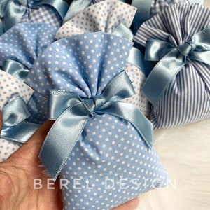 May include: Blue and white fabric gift bags with white polka dots and gingham patterns. The bags are tied with blue satin ribbon bows. The bags are labelled "BEREL DESIGN".
