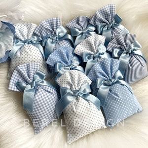 May include: A group of small blue and white fabric bags with blue ribbon ties. The bags are decorated with gingham and polka dot patterns.
