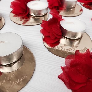 May include: Gold mirrored candle holders with red tulle flowers and tea lights. The holders are engraved with the text "Prenses Yuvadan &Ccedil;ıkıyor".