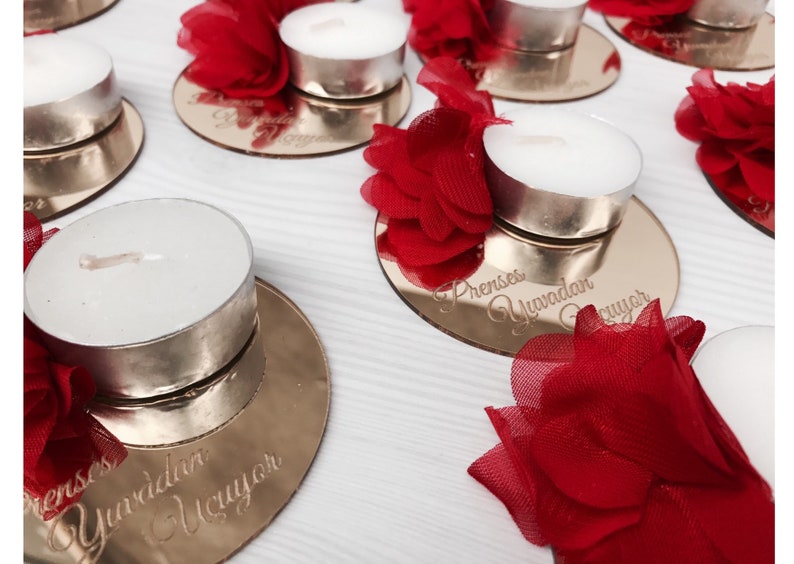 May include: Gold mirrored candle holders with red tulle flowers and tea lights. The holders are engraved with the text "Prenses Yuvadan &Ccedil;ıkıyor".