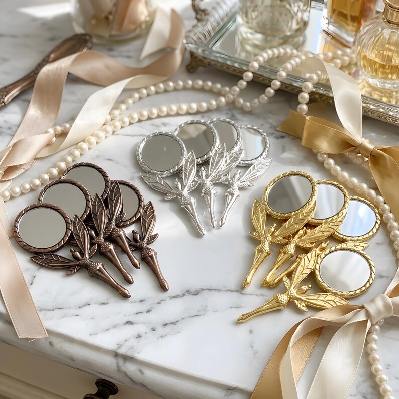 May include: A collection of small handheld mirrors featuring fairy-shaped handles with wings. The mirrors are arranged in three distinct metallic finishes: copper, silver, and gold. Each mirror has a circular glass surface and a detailed handle.