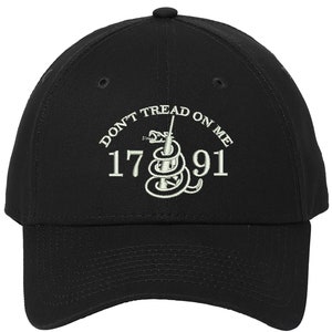 May include: A black baseball cap with an embroidered design featuring a coiled snake with a spear through it, the text "Don't Tread On Me", and the numbers "1776".