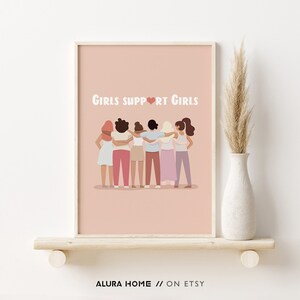 K&ouml;nnte beinhalten: Ein rosa druckbarer Poster mit dem Text "Girls Support Girls" in wei&szlig;en Buchstaben mit einem rosa Herzen in der Mitte des Wortes "Support". Das Poster zeigt eine Gruppe von sechs verschiedenen Frauen, die mit ihren Armen umeinander stehen.