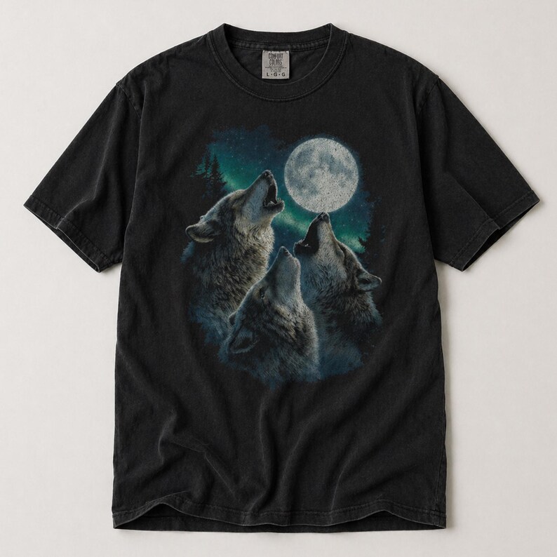 May include: Black t-shirt with a graphic of three wolves howling at a full moon. The design includes a night sky with a full moon and a forest silhouette. The shirt is a crew neck and has short sleeves.