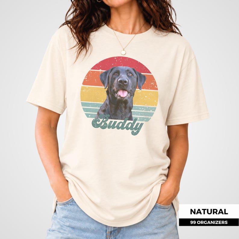 Personalized pet photo tee featuring a custom dog portrait framed by a circular retro sunset with distressed multicolor stripes and a nostalgic vintage finish. The dog’s name appears prominently underneath in cream script lettering. This custom design also works with cat photos, making it a thoughtful personalized gift for pet parents, dog and cat lovers, birthdays, holidays, adoption celebrations, pet memorials, and anyone who wants to wear a portrait of their companion.