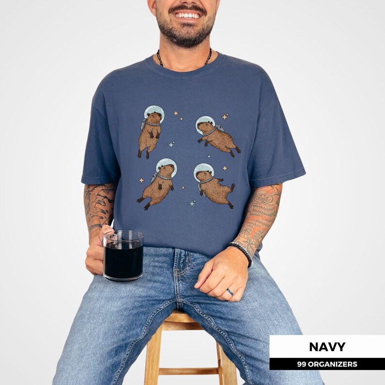 Adorable astronaut capybara tee—funny, bold, and whimsical. Ideal for those who love animals, space, and standout humor. Appeals to capybara fans, vintage shirt collectors, and lovers of retro cottagecore or weirdcore clothing.