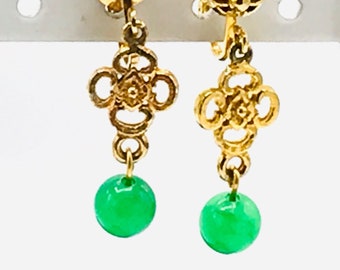 May include: Gold earrings with a green jade stone drop. The earrings have a delicate, intricate design.