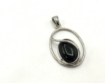 May include: A silver pendant with a black oval gemstone set in a swirling silver design.
