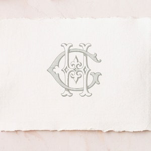 Może przedstawiać: Jasnoszary wz&oacute;r monogramu z przeplatającymi się literami "H" i "C" na teksturowanym, kremowym papierze. Papier ma postrzępioną krawędź, na tle miękkiego r&oacute;żowego tła.