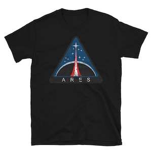 Puede incluir: Camiseta negra con un logotipo triangular desgastado en azul, rojo y blanco con el texto "ARES" debajo.