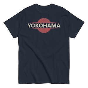 Puede incluir: Una camiseta azul marino con un círculo rojo y la palabra "YOKOHAMA" en texto blanco.