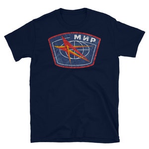 Könnte beinhalten: Ein marineblaues T-Shirt mit einem Patch im Vintage-Stil, der einen roten Stern und das Wort "МИР" in kyrillischer Schrift zeigt.