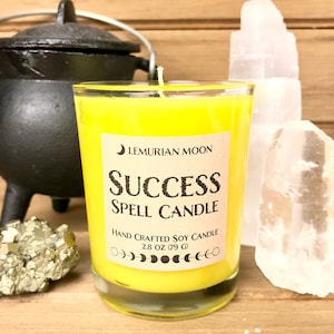 Puede incluir: Vela de soja amarilla con una etiqueta que dice "Lemurian Moon Success Spell Candle Hand Crafted Soy Candle 2.8 oz (79 g)".