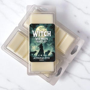 May include: Two clear plastic clamshell containers filled with off-white wax melts. The label features a full moon, a silhouette of a person, and wolves in a forest with the text Witch Wax Melts, Damp Woods, Apple, Nutmeg, Clove, Lemurian Moon, 2 Ounces.