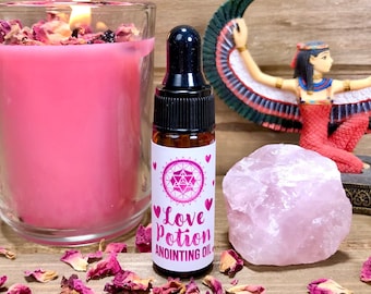 Puede incluir: Un pequeño frasco de vidrio marrón con un gotero lleno de un líquido transparente. El frasco tiene una etiqueta blanca con corazones rosas y el texto "Love Potion Anointing Oil".