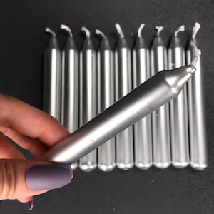 May include: A group of silver candle sticks, some are lit and some are not. The candles are approximately 15 cm long.